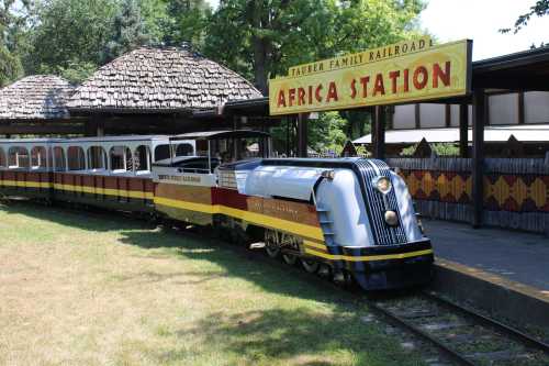 A vintage train at Africa Station, featuring colorful cars and a distinctive locomotive, surrounded by greenery.