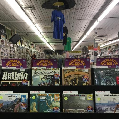 A vintage record store interior with shelves of vinyl records and a blue T-shirt hanging from the ceiling.