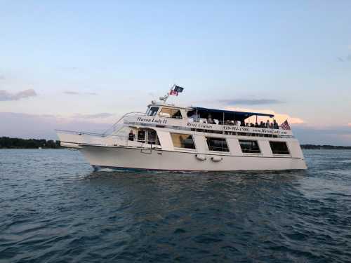 A white passenger boat named "Harbor Lady II" cruising on calm waters with flags waving in the breeze.