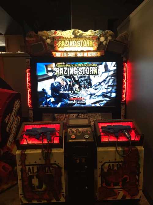 An arcade game machine for "Razing Storm" featuring a large screen and two gun controllers.