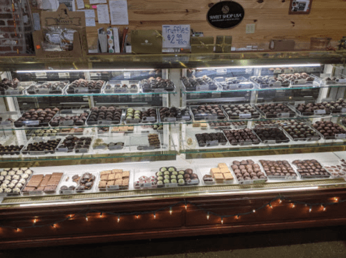 A display case filled with various chocolate truffles and confections, neatly arranged and illuminated.