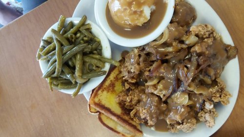 A plate of fried chicken with gravy, green beans, mashed potatoes, and toast.