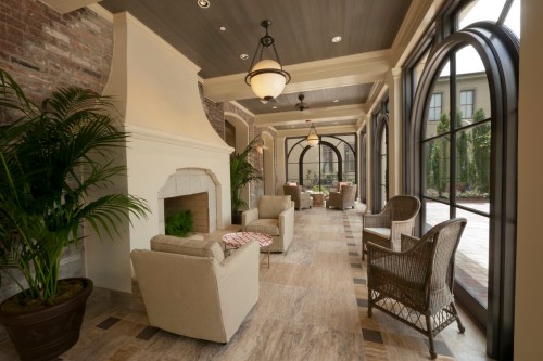 Cozy lounge area with a fireplace, comfortable seating, and large arched windows overlooking a garden.