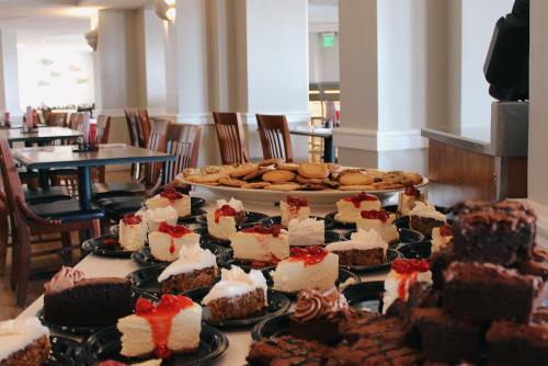 A display of assorted desserts, including cheesecake with toppings, brownies, and cookies, in a dining area.