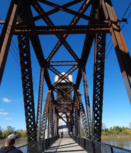 View from beneath a metal bridge, showcasing its intricate structure against a clear blue sky.