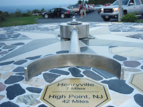 A metal marker on a stone compass rose, indicating directions and distances to nearby locations.