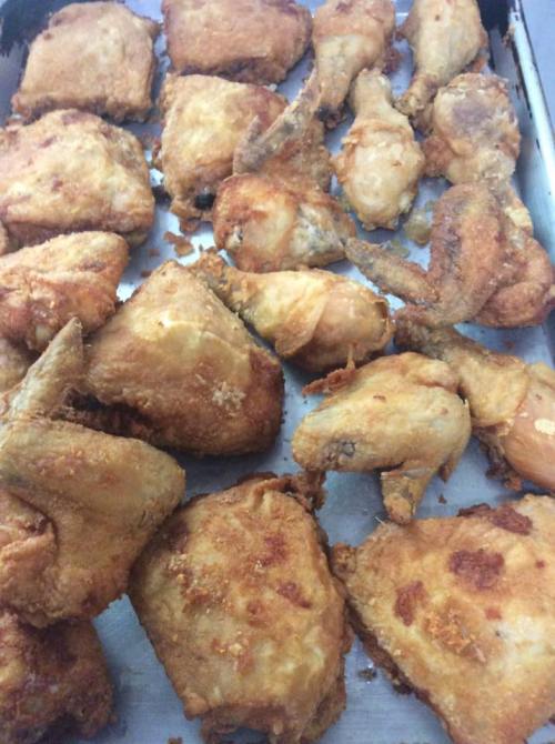 A tray of golden-brown fried chicken pieces, including wings and drumsticks, arranged neatly.