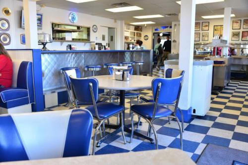 A retro diner interior featuring blue and white decor, a round table, and chrome chairs.