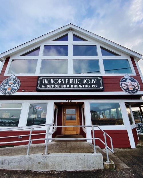 Exterior of The Horn Public House and Depoe Bay Brewing Co., featuring large windows and a welcoming entrance.