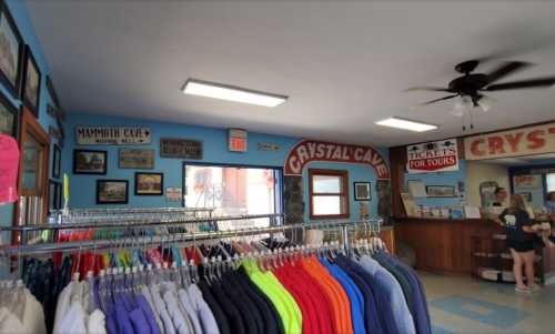 Interior of a gift shop with colorful clothing racks, vintage signs, and a ticket counter for cave tours.