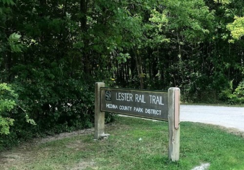 Sign for Lester Rail Trail, Meda County Park District, surrounded by greenery and trees.