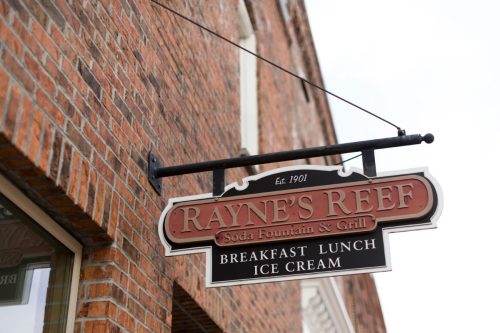 Sign for Rayne's Reef Soda Fountain & Grill, established 1901, offering breakfast, lunch, and ice cream.