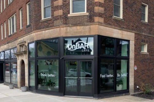 Exterior of UnBAR Cafe with large windows displaying the phrases "Think better. Feel better." on a brick building.