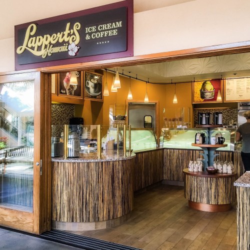 A cozy ice cream and coffee shop interior with a wooden counter and colorful menu displays.