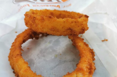 Two crispy, golden-brown onion rings on a white paper background.
