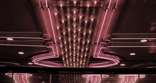 A ceiling adorned with pink neon lights and decorative bulbs, creating a vibrant, retro atmosphere.