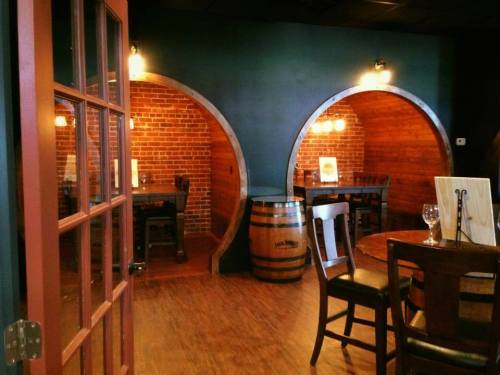 Cozy restaurant interior featuring brick walls, wooden barrels, and intimate dining spaces with warm lighting.