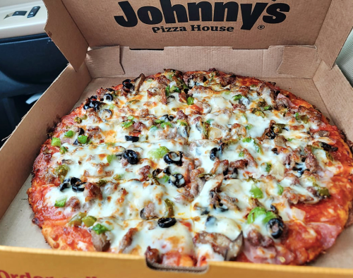 A pizza topped with cheese, olives, green peppers, and meat, inside a Johnny's Pizza House box.