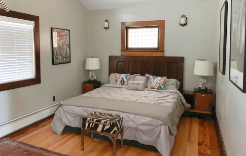 Cozy bedroom featuring a large bed, decorative pillows, nightstands, and stylish artwork on the walls.