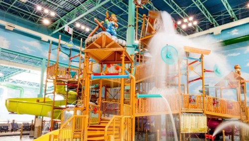 Colorful indoor water park play structure with slides, water features, and playful decorations.