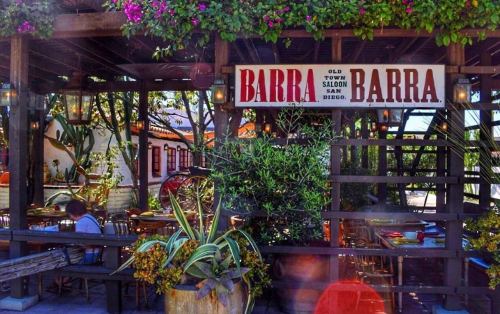 A charming outdoor dining area with greenery and a sign reading "Barra Barra" in Old Town San Diego.