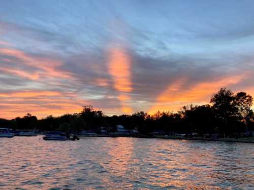 A serene lake at sunset, with vibrant orange and pink clouds reflecting on the water's surface.