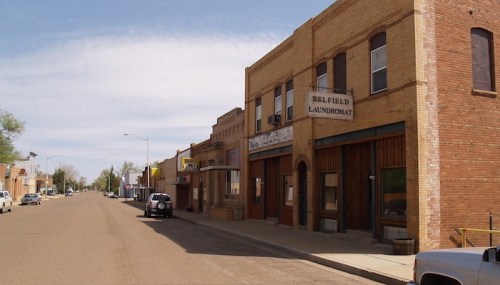A quiet street scene featuring brick buildings, including a laundromat, under a clear blue sky.