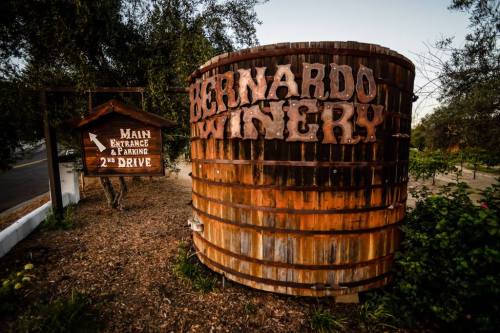 Sign for Bernardo Winery with a wooden barrel and a directional sign for main entrance and parking.