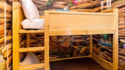 A wooden bunk bed in a colorful, nature-themed room with a mural of animals on the walls.