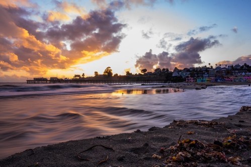 A serene beach scene at sunset, with waves gently lapping the shore and colorful clouds in the sky.