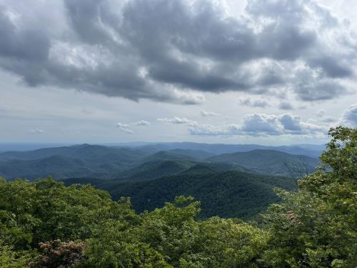 A panoramic view of rolling green mountains under a cloudy sky.