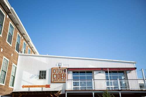 Exterior of Citizen Cider building with a clear blue sky above and a wooden deck in front.