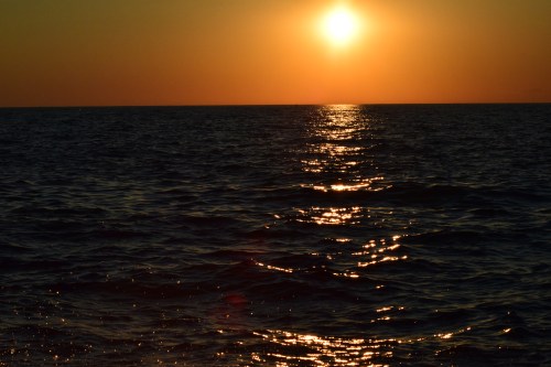 A serene sunset over the ocean, with golden sunlight reflecting on the water's surface.