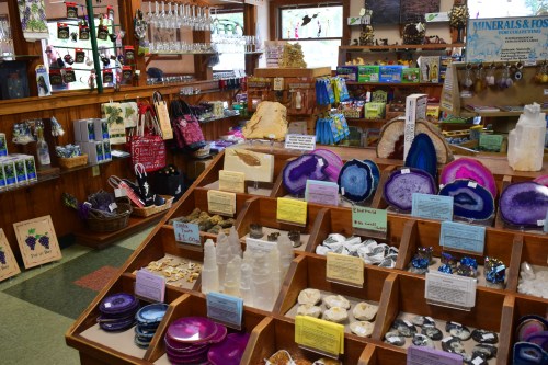 A colorful display of minerals and crystals in a shop, with various items arranged on wooden shelves and tables.