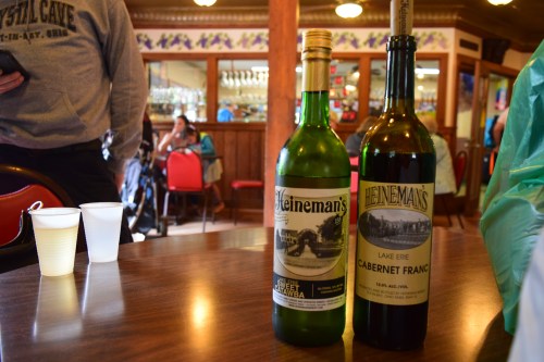 Two bottles of Heineman's wine on a table, with a blurred background of a restaurant and people.