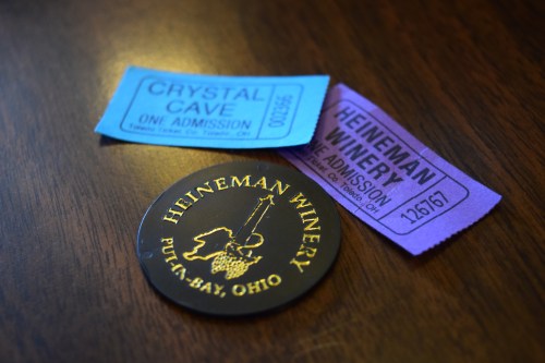 A black coaster with "Heineman Winery" logo, alongside two admission tickets for Crystal Cave and Heineman Winery.