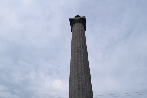A tall stone column with a flat top, set against a cloudy sky.