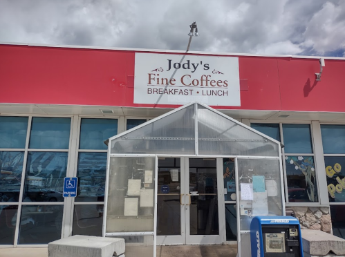 Exterior of Jody's Fine Coffees, featuring a red sign and a glass entrance, with a blue mailbox nearby.