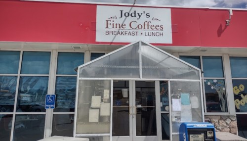 Exterior of Jody's Fine Coffees, a breakfast and lunch spot, featuring a glass entrance and a blue mailbox outside.