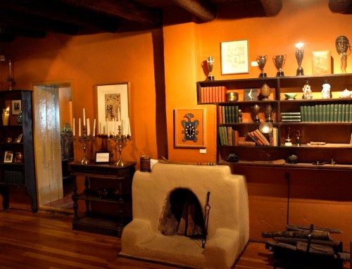 Cozy room with an orange wall, a fireplace, shelves of books, and decorative items, creating a warm, inviting atmosphere.