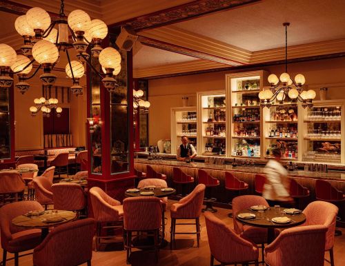 Elegant restaurant interior with plush seating, a well-stocked bar, and warm lighting creating a cozy atmosphere.