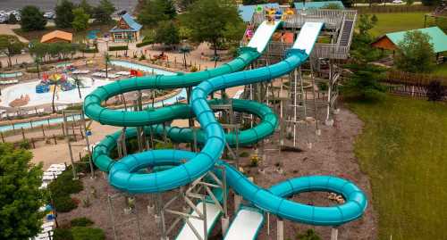 Aerial view of a water park featuring twisting blue water slides and a splash area surrounded by greenery.