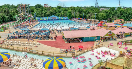 A vibrant water park scene with a large pool, water slides, and people enjoying the sun and attractions.