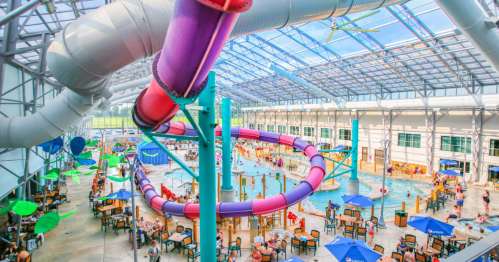 A vibrant indoor water park featuring colorful slides, a large pool, and numerous visitors enjoying the facilities.