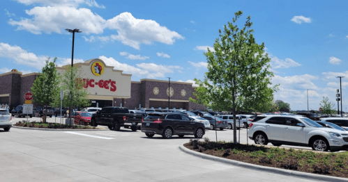 A busy Buc-ee's store with a full parking lot and clear blue skies in the background.