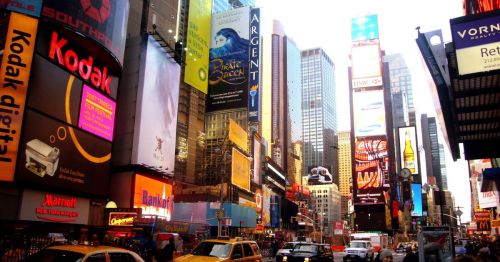 A bustling Times Square scene with bright billboards, skyscrapers, and busy streets filled with cars.