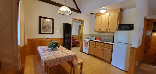 Cozy kitchen and dining area with wooden accents, a table, and appliances including a stove and refrigerator.