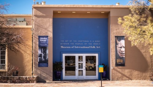 Entrance of the Museum of International Folk Art, featuring banners and a welcoming doorway.