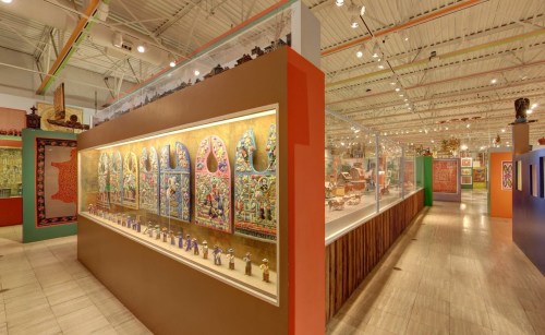 A brightly lit museum interior showcasing colorful art displays and intricate sculptures along the walls.