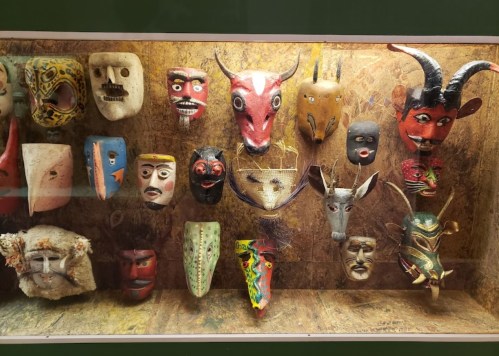 A display of various colorful masks arranged on a wall, showcasing diverse designs and cultural styles.